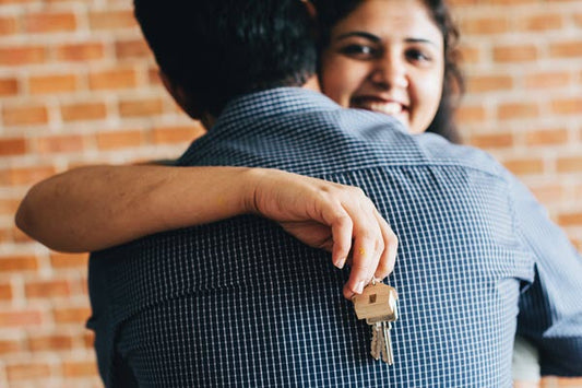 Couple embrace; woman is holding keys.