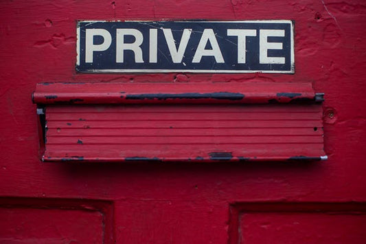 Close-up of red door with PRIVATE sign above mail slot