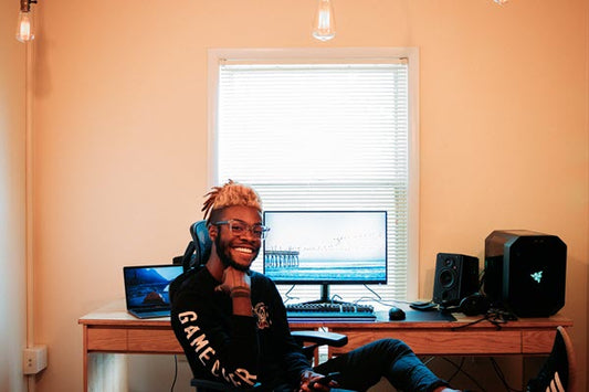 Young man sitting at computer with speaker visible on desk