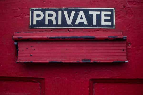 Close-up of red door with PRIVATE sign above mail slot